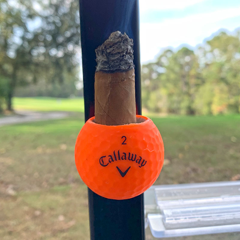 Orange Callaway Cigar Ball holding a cigar attached to a golf cart